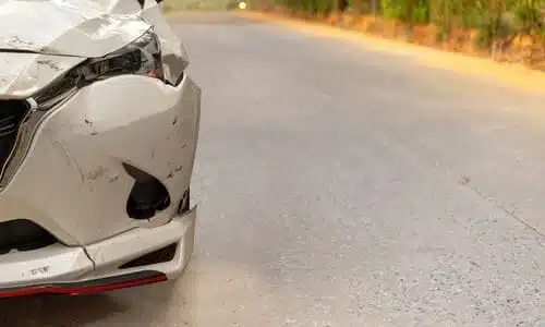 الجزء الأمامي المتضرر لسيارة بيضاء متوقفة على جانب الطريق