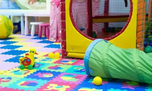 منطقة لعب داخلية ملوّنة تحتوي على حصائر إسفنجية وألعاب بلاستيكية ونفق لعب، تمثل بيئة حادث في دار رعاية أطفال.