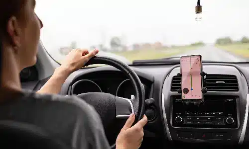 سائقة نقل تشاركي تنظر إلى جهاز الملاحة أثناء القيادة.