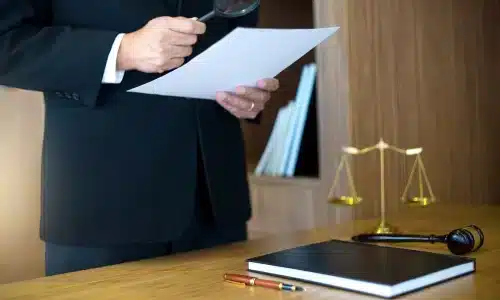 محامي قضايا عضات الكلاب في غينزفيل يقرأ مستندًا باستخدام عدسة مكبرة أثناء وقوفه في مكتبه.
