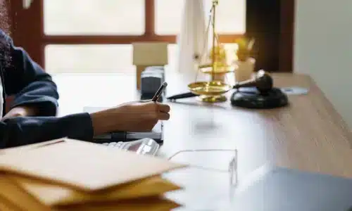 لقطة مقربة ليد محامي قضايا الإهمال في غينزفيل وهو يكتب في دفتر على مكتب داخل مكتبه.