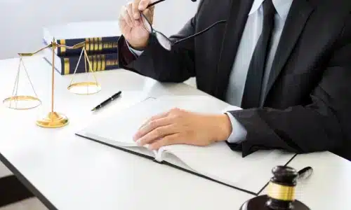 محامي قضايا مسؤولية الأماكن في غينزفيل يمسك نظارته أثناء قراءة مستند على مكتب.