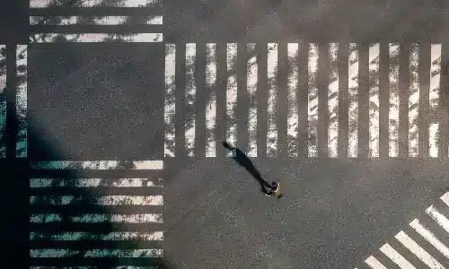 لقطة علوية لمشاة يعبرون تقاطعًا مزدحمًا في وضح النهار.