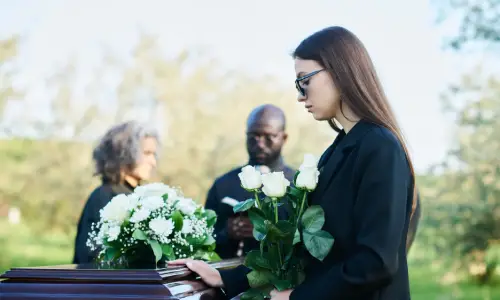 امرأة تمسك بباقة زهور بيضاء في جنازة ضحية وفاة خطأ.
