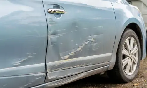 سيارة بلون رمادي مزرق بباب متضرر نتيجة حادث هروب بعد التصادم