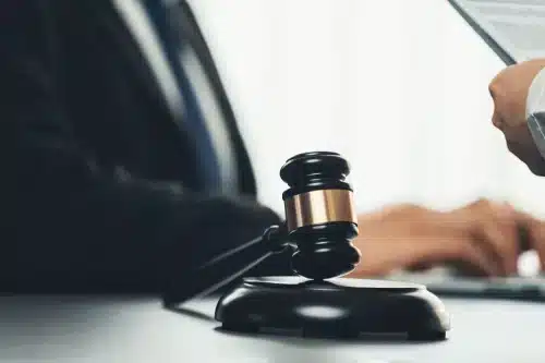 محامٍ مختص بقضايا الإصابات الشخصية يكتب على حاسوب محمول بينما يقرأ عميل شروط وثيقة التأمين.