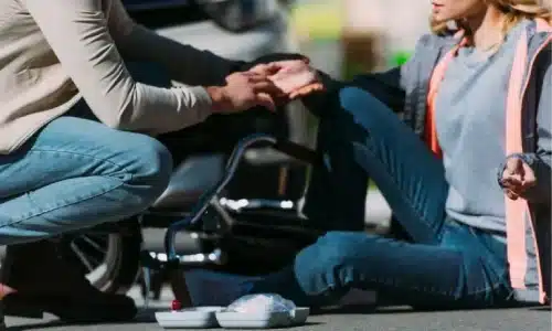 سائق دراجة نارية يساعد امرأة صدمها خلال حادث وقع في النهار.