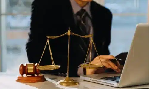 محامٍ مختص بقضايا الإصابات الشخصية يعمل على حاسوب محمول داخل مكتبه لإعداد قضية لعميل.