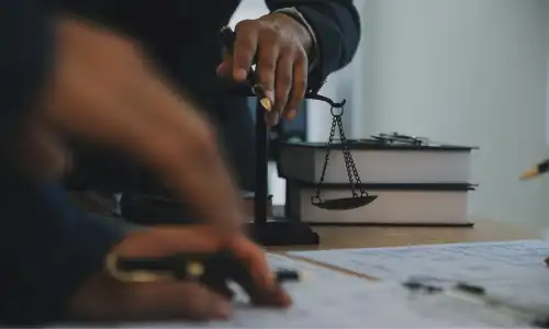 محامٍ يستند إلى ميزان على مكتب أثناء العمل مع عميل في قضية حادث بناء