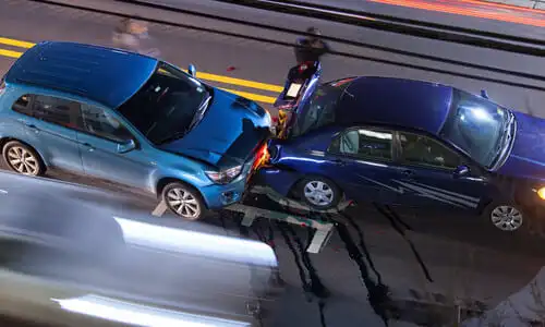لقطة علوية بتعريض ضوئي طويل لحادث تصادم بين مركبتين بينما تمر حركة المرور بجوارهما.