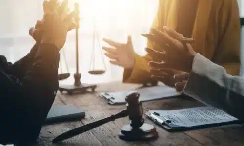 لقطة قريبة لاستشارة قانونية بين موكل ومحاميين، ترمز إلى مناقشة قضية تعويضات العمال.