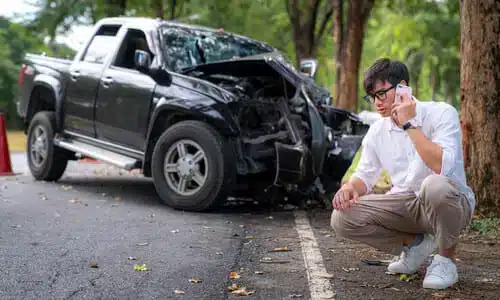 رجل يقف وبالخلفية شاحنة صغيرة متضررة بعد حادث هروب من موقع التصادم