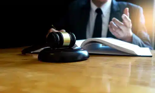 محامي إصابات دماغية في أريزونا يقرأ كتابًا مفتوحًا على الطاولة ويشير بيده اليسرى.