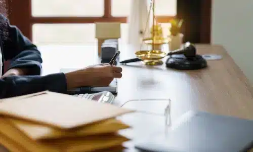 محامية حوادث إنشاءات في أريزونا تكتب على مكتبها، مغلفات على يمينها وميزان عدالة على يسارها.
