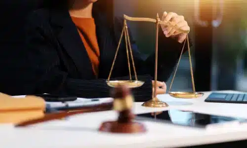 محامي حوادث قيادة تحت التأثير يجلس في مكتب بأريزونا تحيط به ملفات، آلة حاسبة وميزان عدالة على المكتب.
