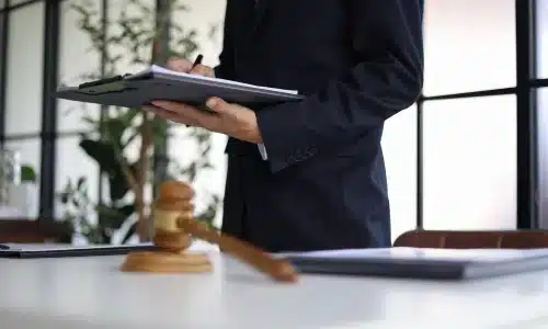 محامية إصابات شخصية تقف داخل مكتب محاماة في أريزونا وتحمل ملفًا على لوحة كتابة بيدها.