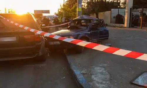 حادث سيارات في شارع داخل المدينة مع أضرار وشريط شرطة أحمر وأبيض يؤمّن الموقع.