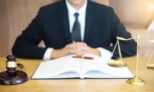 محامي حوادث الدراجات الهوائية يضع يديه على طاولة المكتب داخل مكتب محاماة في هيوستن أثناء قراءة كتاب قانون مفتوح.