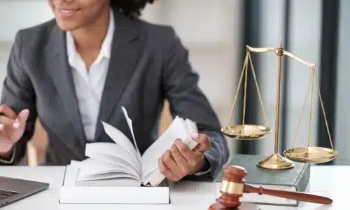 محامية حوادث مواقع البناء تبتسم أثناء قراءة كتاب قانون داخل مكتبها في هيوستن.