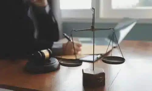محامٍ يجلس خلف مكتب ويفتح مظاريف تحتوي على مستندات تتعلق بقضية إصابة شخصية لأحد العملاء.