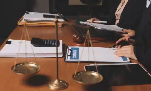 محامي حوادث السائق غير المؤمن عليه يتحدث مع زميل أثناء قراءة ملفات قضية موضوعة على الطاولة داخل مكتب محاماة في هيوستن.
