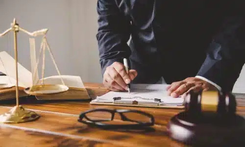محامي قضايا الوفاة غير المشروعة يقف داخل مكتب محاماة في هيوستن أثناء توقيع المستندات.