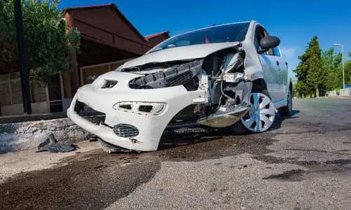 سيارة بيضاء على طريق فرعي بعد حادث كبير تسبب في تدميرها.