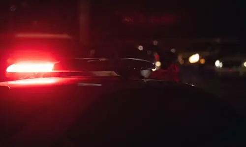 سيارة شرطة وأضواؤها الحمراء تومض ليلاً أثناء الاستجابة لحادث هروب من موقع الحادث.