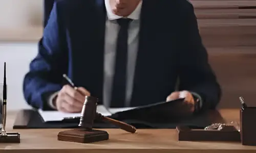 محامي قضايا النقل التشاركي منحنٍ فوق مكتبه وهو يعمل على ملف قضية.