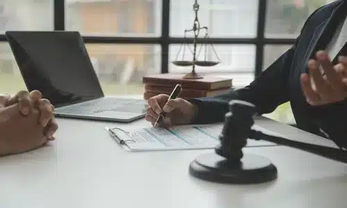 محامية إهمال في نوجاليس تناقش قضية مع عميلة وتدوّن الملاحظات، مع مطرقة قاضٍ على الطاولة.