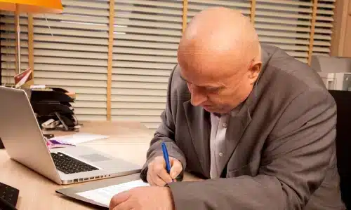 محامي وفاة غير مشروعة في نوجاليس يدوّن ملاحظات أمام حاسوبه وهاتف المكتب.