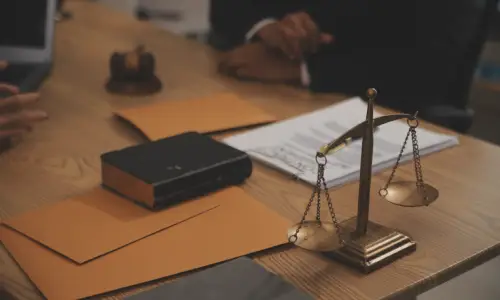 محامٍ لقضية منتج معيب يجلس إلى مكتبه وبأمامه أوراق تأمين تخص عميلًا.