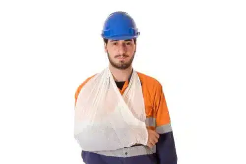 عامل بناء شاب مصاب وذراعه معلّقة بحمالة طبية.