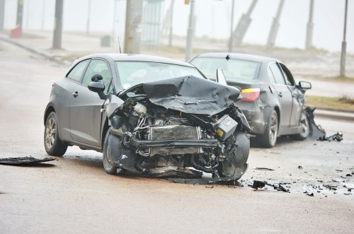 Se muestra un accidente automovilístico grave después del choque. Un auto gris tiene la parte delantera destrozada.