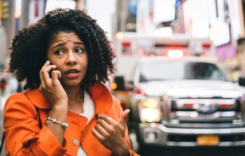 Una mujer habla por teléfono con la compañía de seguros después de un accidente con un conductor sin seguro.