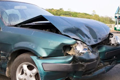 Un automóvil azul opaco con la parte delantera dañada después de un accidente automovilístico a alta velocidad.
