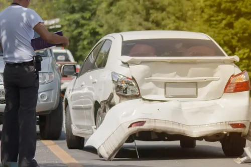 Una persona que documenta daños a su vehículo después de un accidente automovilístico para un reclamo de seguro.