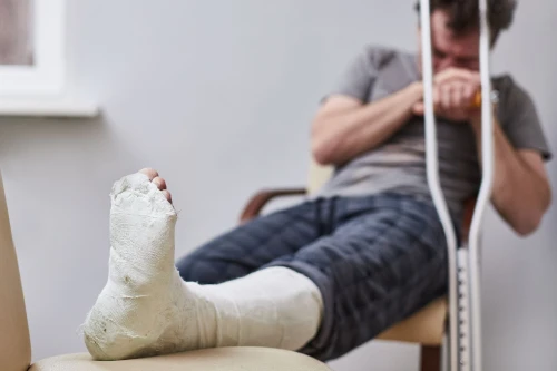 Una persona con una pierna lesionada en un accidente automovilístico esperando en el vestíbulo de un hospital.
