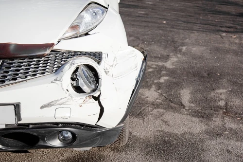 La parte delantera de un vehículo blanco dañada en un accidente por conducir en estado de ebriedad.