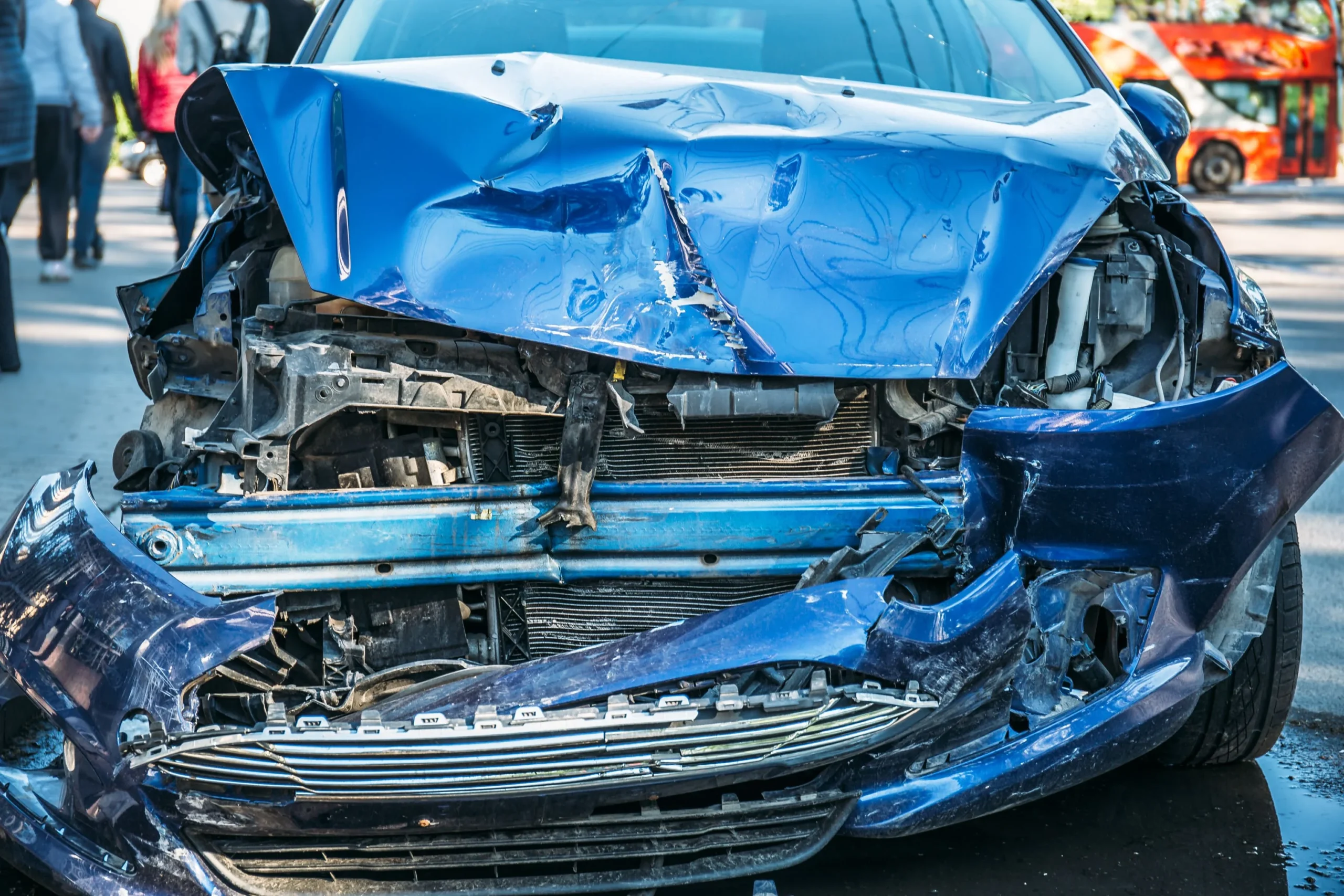 Un coche azul con daños en la parte delantera tras un accidente automovilístico.