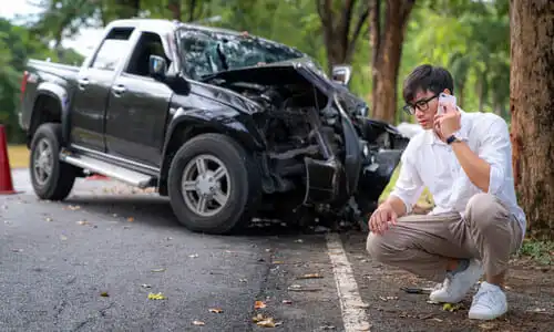 Un hombre con una camioneta accidentada al fondo después de un accidente de choque y fuga.