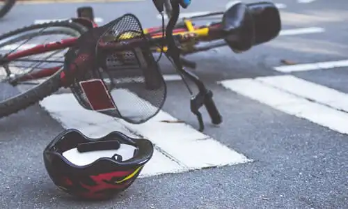 Una bicicleta infantil con una cesta volcada tras un accidente en un cruce de peatonal.