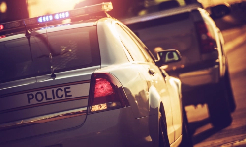 Un auto de policía deteniéndose detrás de otro vehículo en el sito de un accidente automovilístico.