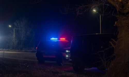 Un auto de patrullaje detenido próximo a la escena de un accidente en la calle de noche.