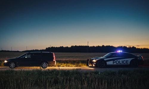 Una captura de largo alcance del vehículo de un oficial policial detenido detrás de otro auto en la carretera en la tarde.
