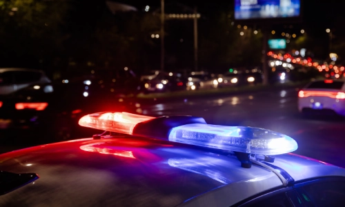 Las luces prendidas de un vehículo policial mientras maneja a través de la calle de la ciudad de noche.