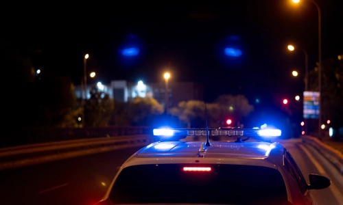 La vista de una azotea de un vehículo policial y sus luces mientras maneja en la tarde.