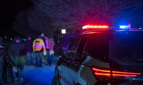 Una multitud de oficiales policiales y testigos a un accidente juntos y discutiendo cerca de un vehículo policial.