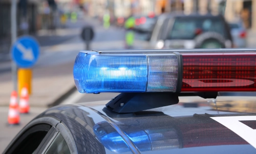 Una toma de cerca de las luces de emergencia de un coche de policía encendidas a plena luz del día.