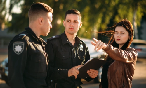 Una mujer explicando a dos oficiales de policía lo que sucedió en la escena de un accidente.